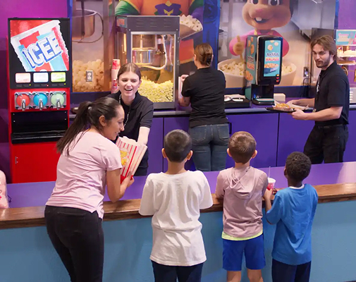 Families ordering popcorn and frozen drinks at the Power Up snack station counter