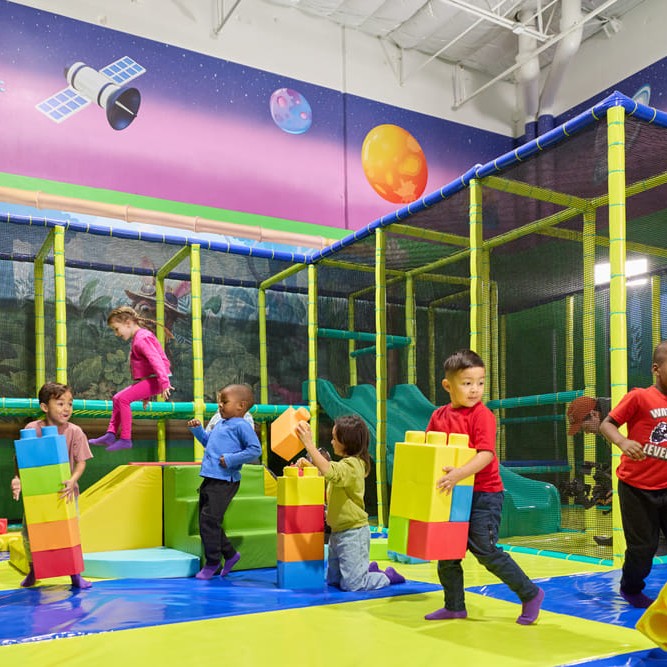 Toddlers stacking soft blocks in Munch&rsquo;s Cosmic Bounce