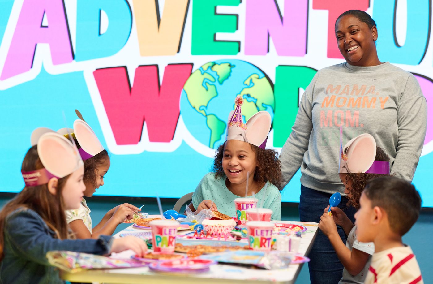 A birthday star and her guests around a decorated party table at Adventure World