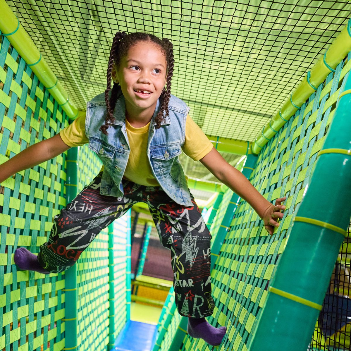 A girl climbing through the rope netting inside the Adventure World play structure