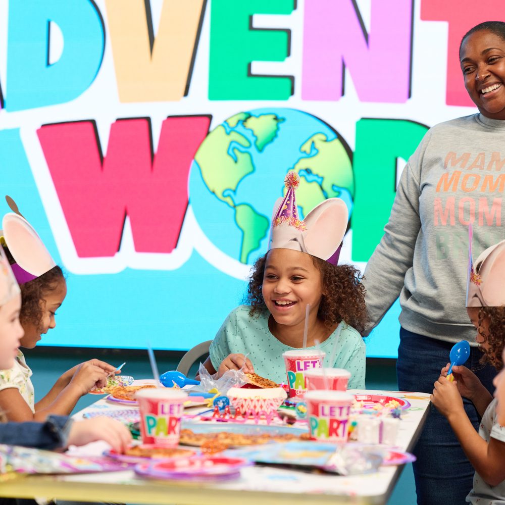 Kids and a team member around a decorated party table at Adventure World